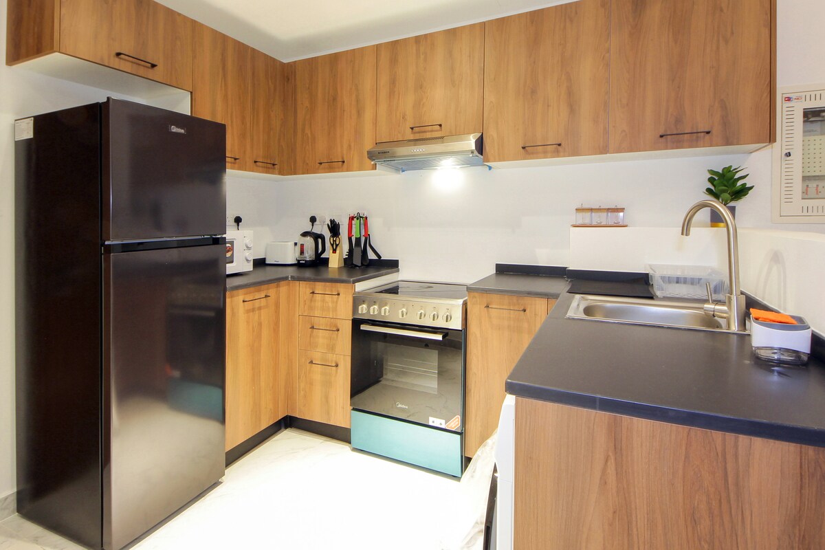 Warm wood kitchen with black worktops and integrated appliances