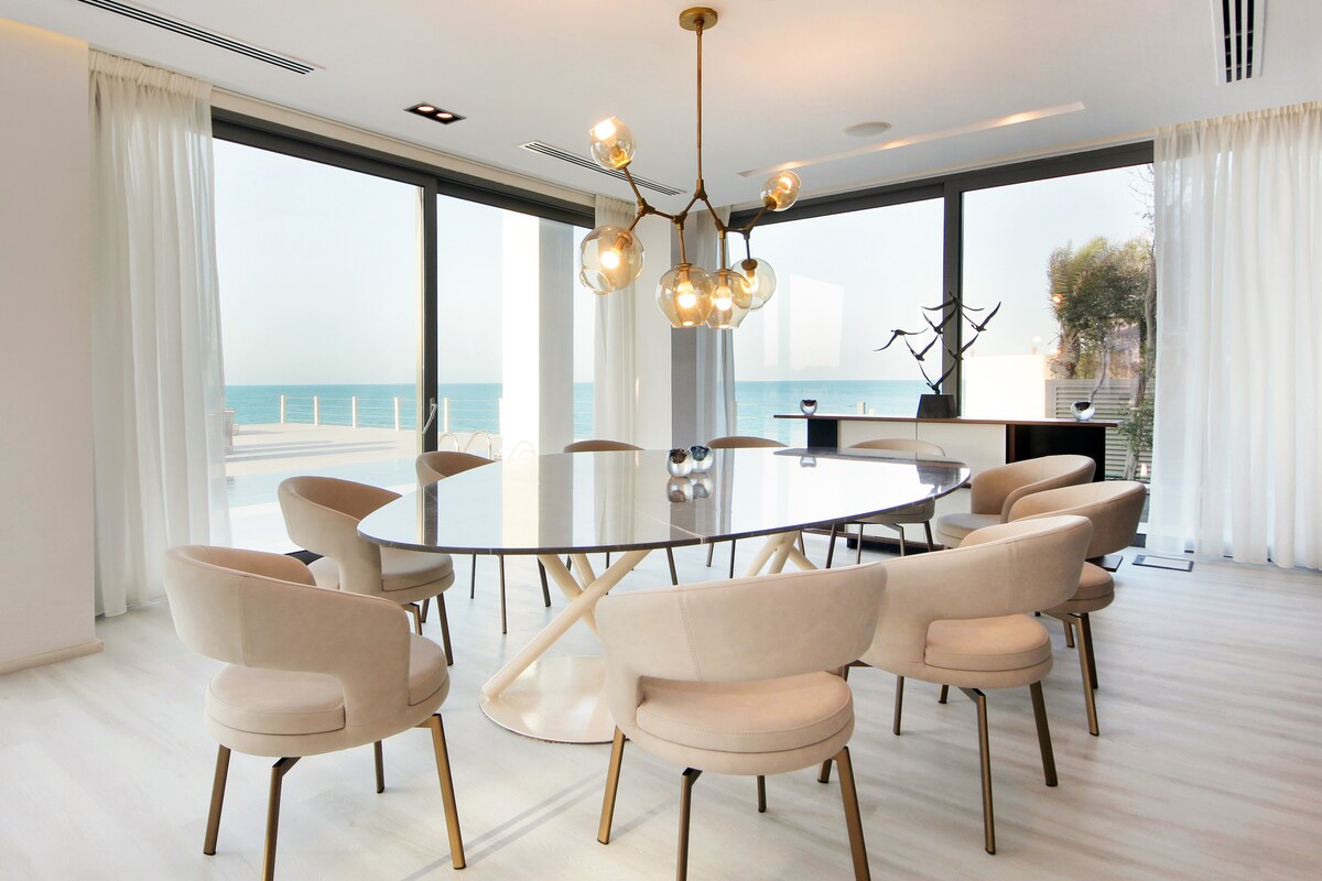 Sculptural dining area beside floor-to-ceiling ocean windows
